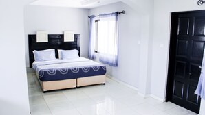 A bedroom with a bed, a window with curtains, and a door. - Sunu Hotel (Serrekunda)