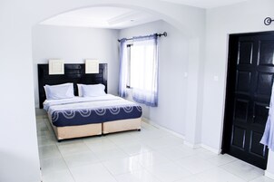 A bedroom with a bed, a window with curtains, and a door.