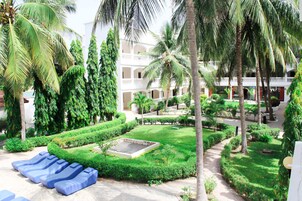 A courtyard with a pool, palm trees, and a building with balconies.