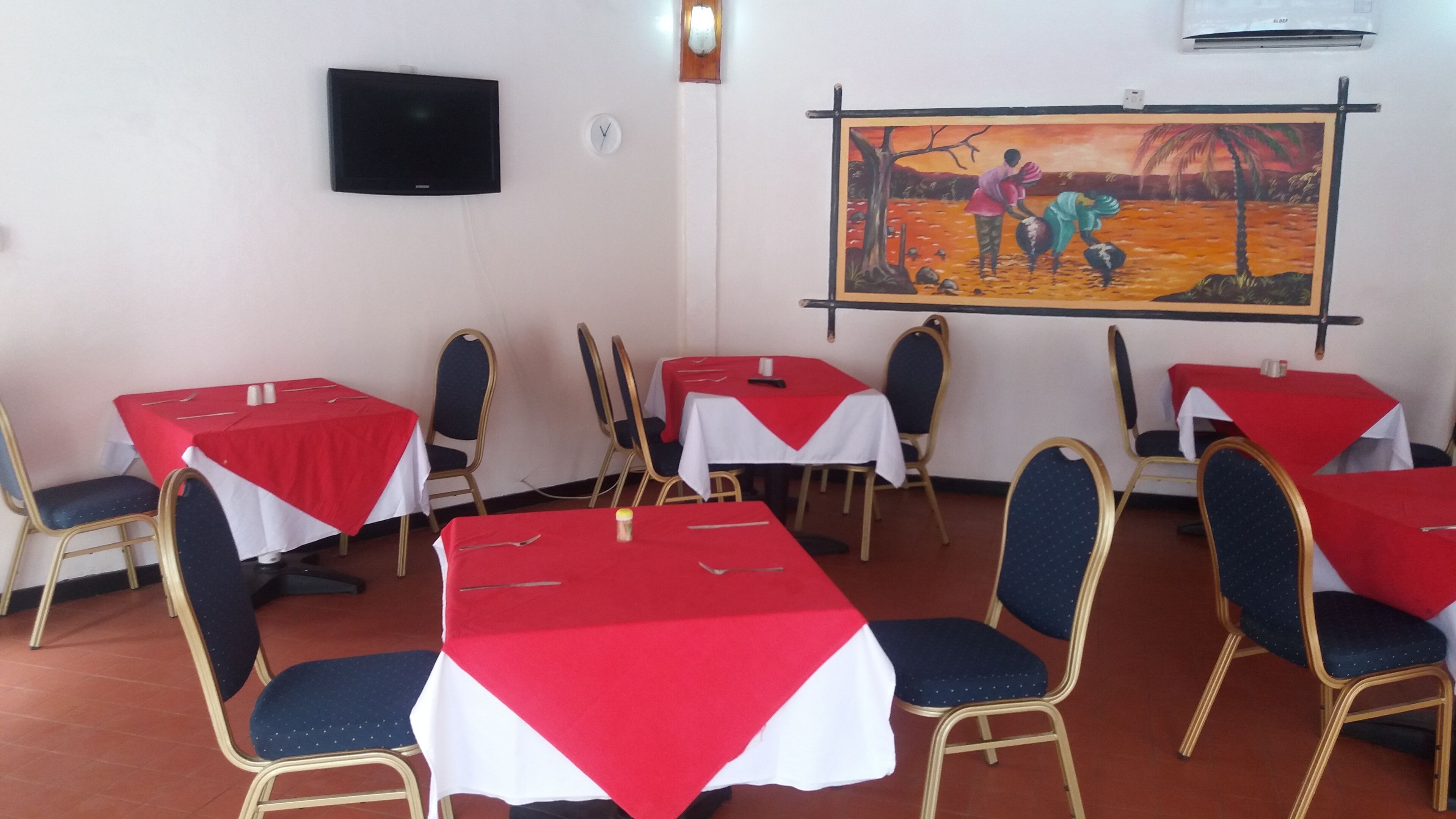 Une salle de conférence avec des tables disposées pour les réunions, une horloge, un téléviseur et un tableau accroché au mur.