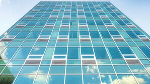 A modern high-rise building with a grid of windows reflecting the sky.