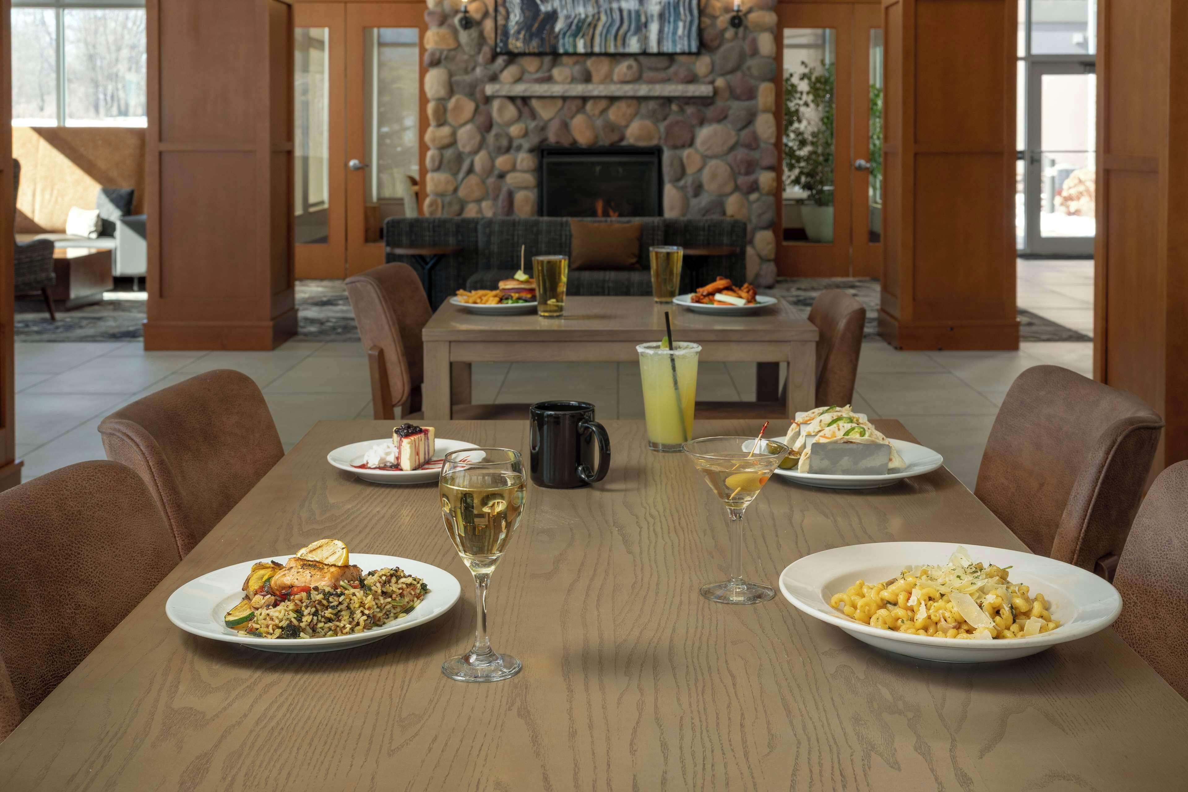 Una mesa de comedor dispuesta con diferentes platos, bebidas y una chimenea al fondo.