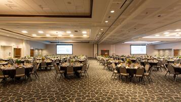 A large conference room with multiple tables set for a meeting, equipped with projectors and screens.
