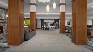 A spacious lobby with a central seating area, a reception desk, and a store. - Hilton Garden Inn Cedar Falls (Cedar Falls)