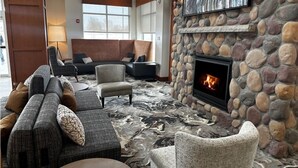 A modern lobby with a stone fireplace, comfortable seating, and a large window. - Hilton Garden Inn Cedar Falls (Cedar Falls)