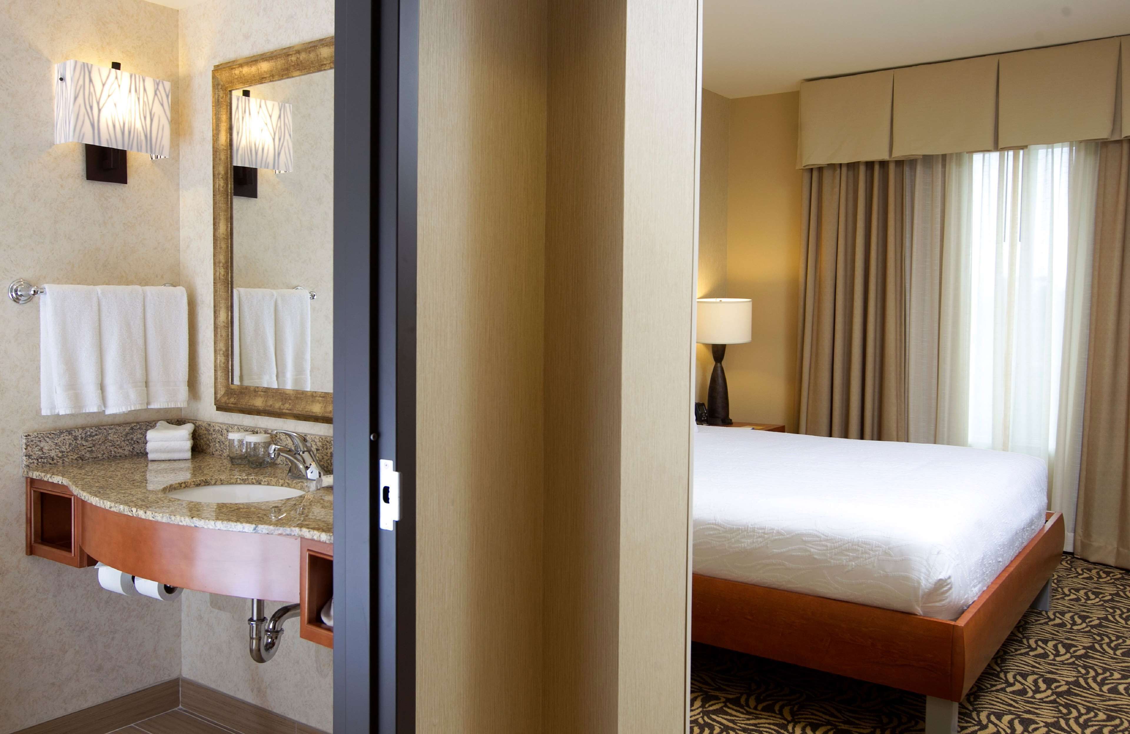 Une salle de bain d’hôtel avec un lavabo en granit, un miroir et un porte-serviettes.