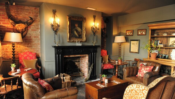 A traditional room with a fireplace, leather furniture, and a brick wall. - The Pig in the Wall (Southampton)