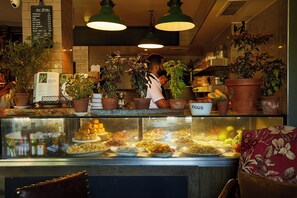 Een bakkerij etalage met diverse gebakken producten en een menubord erboven.