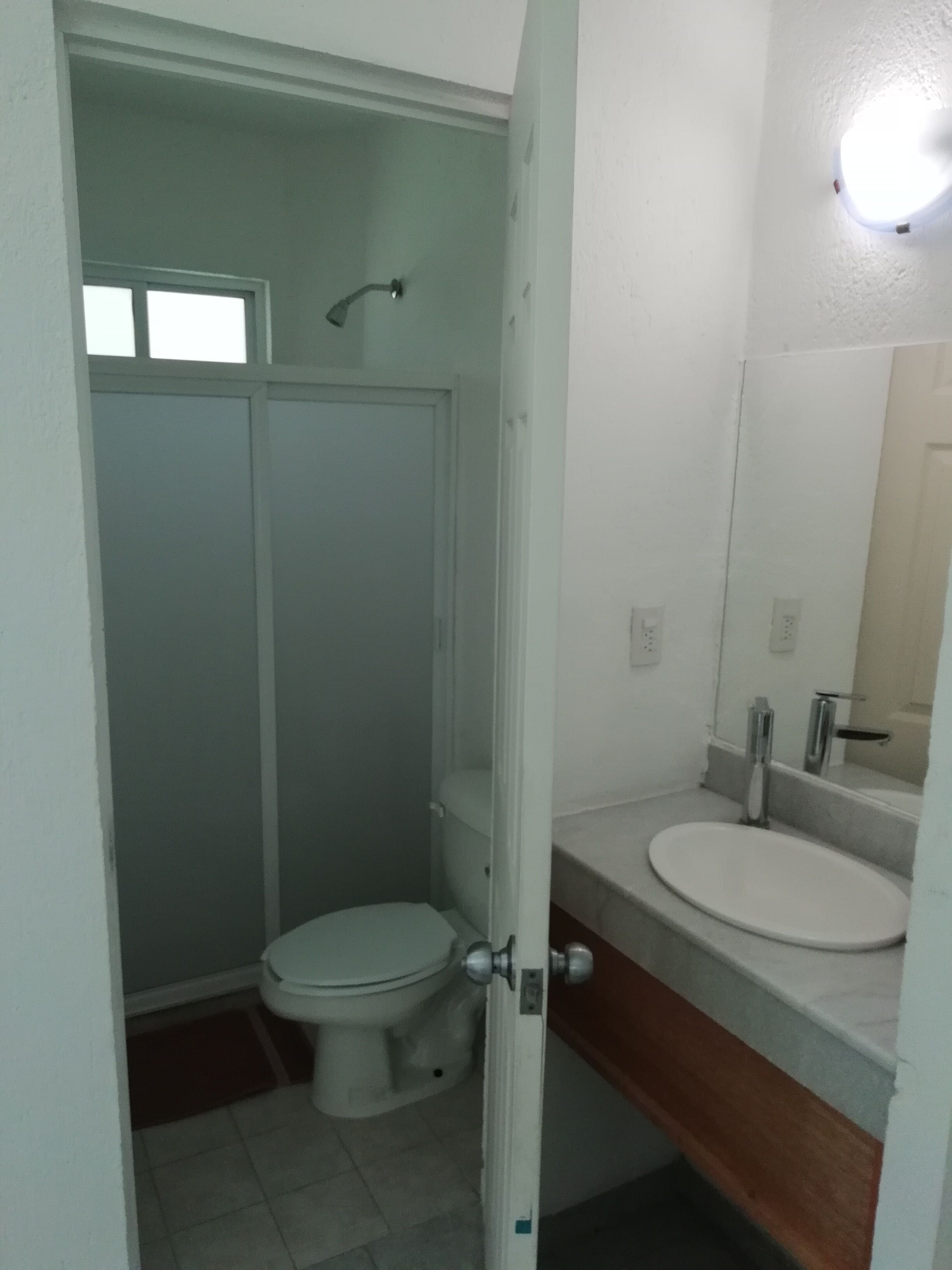 Un baño pequeño y funcional con inodoro, lavamanos y ducha.