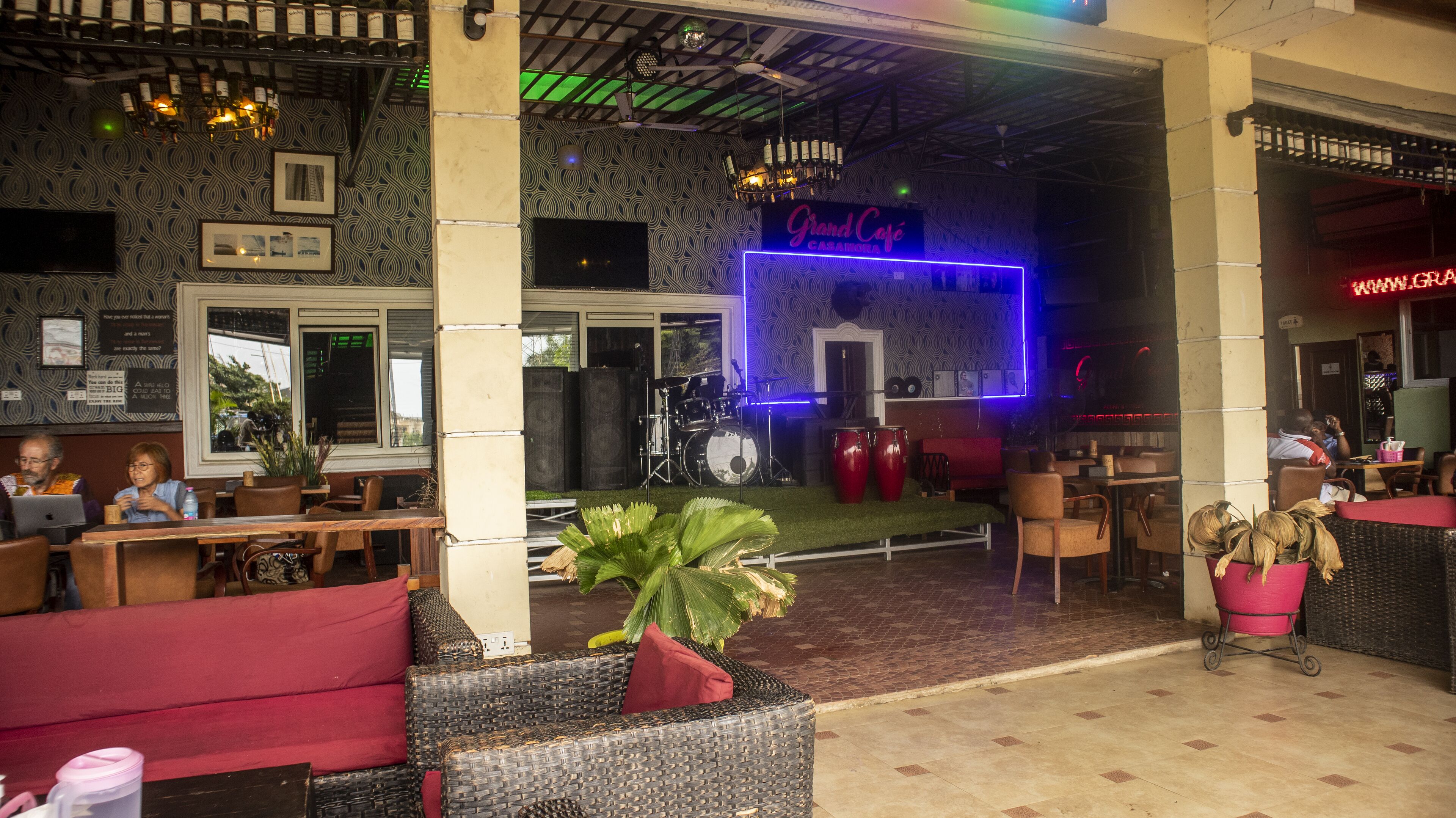 An outdoor seating area with wicker furniture and a stage with musical instruments.
