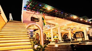 A hotel lobby with a staircase, seating areas, and a reception desk. - Grand Casamora (Accra)