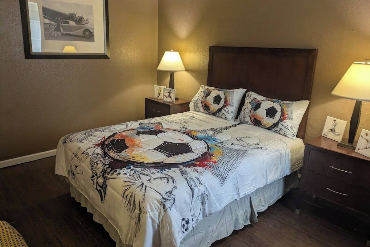 A hotel room with a large bed, two bedside tables, a framed picture on the wall, and a lamp on each table.