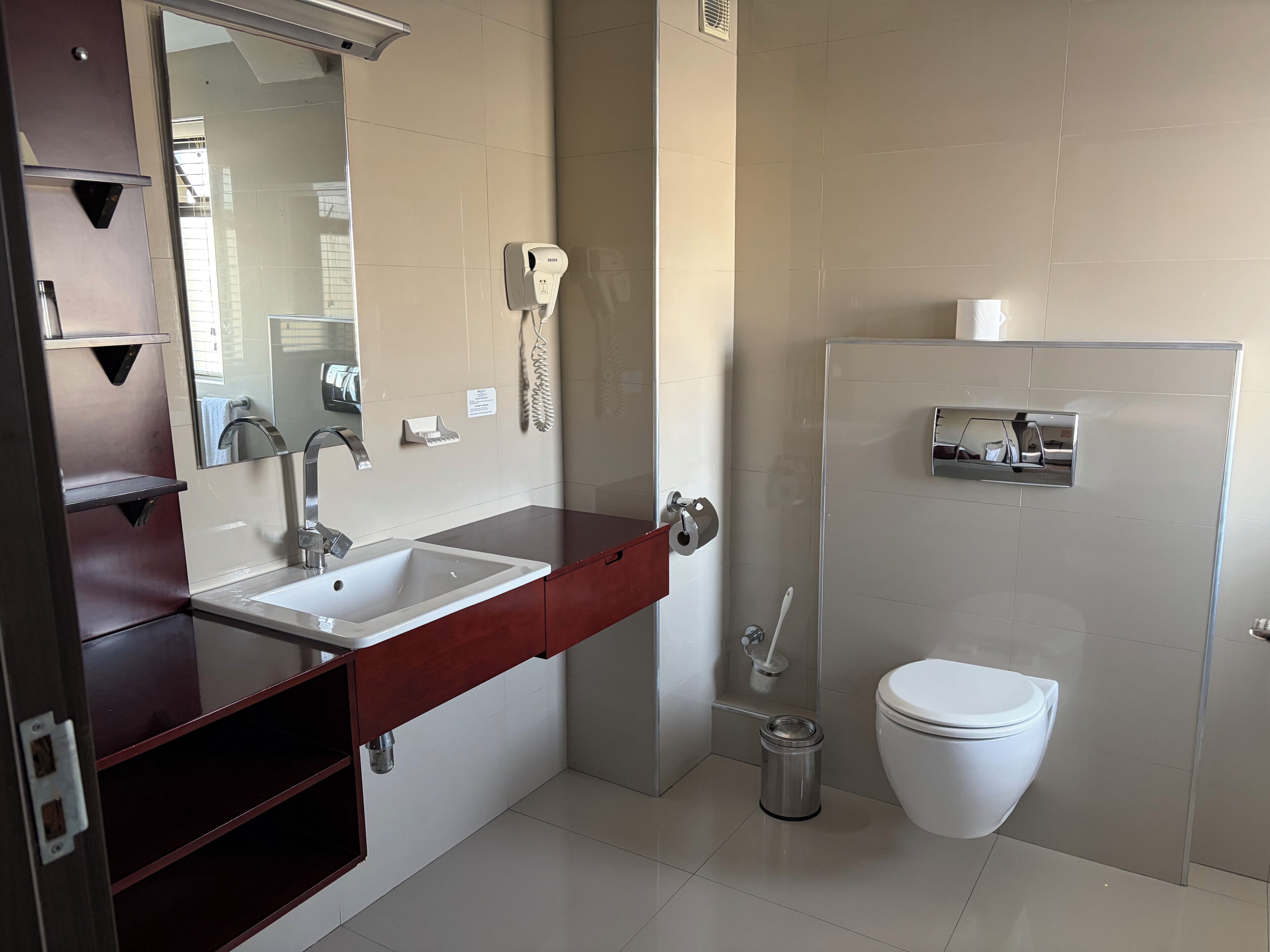 Une salle de bain moderne équipée d’un lavabo, d’un miroir, de toilettes et d’une poubelle.