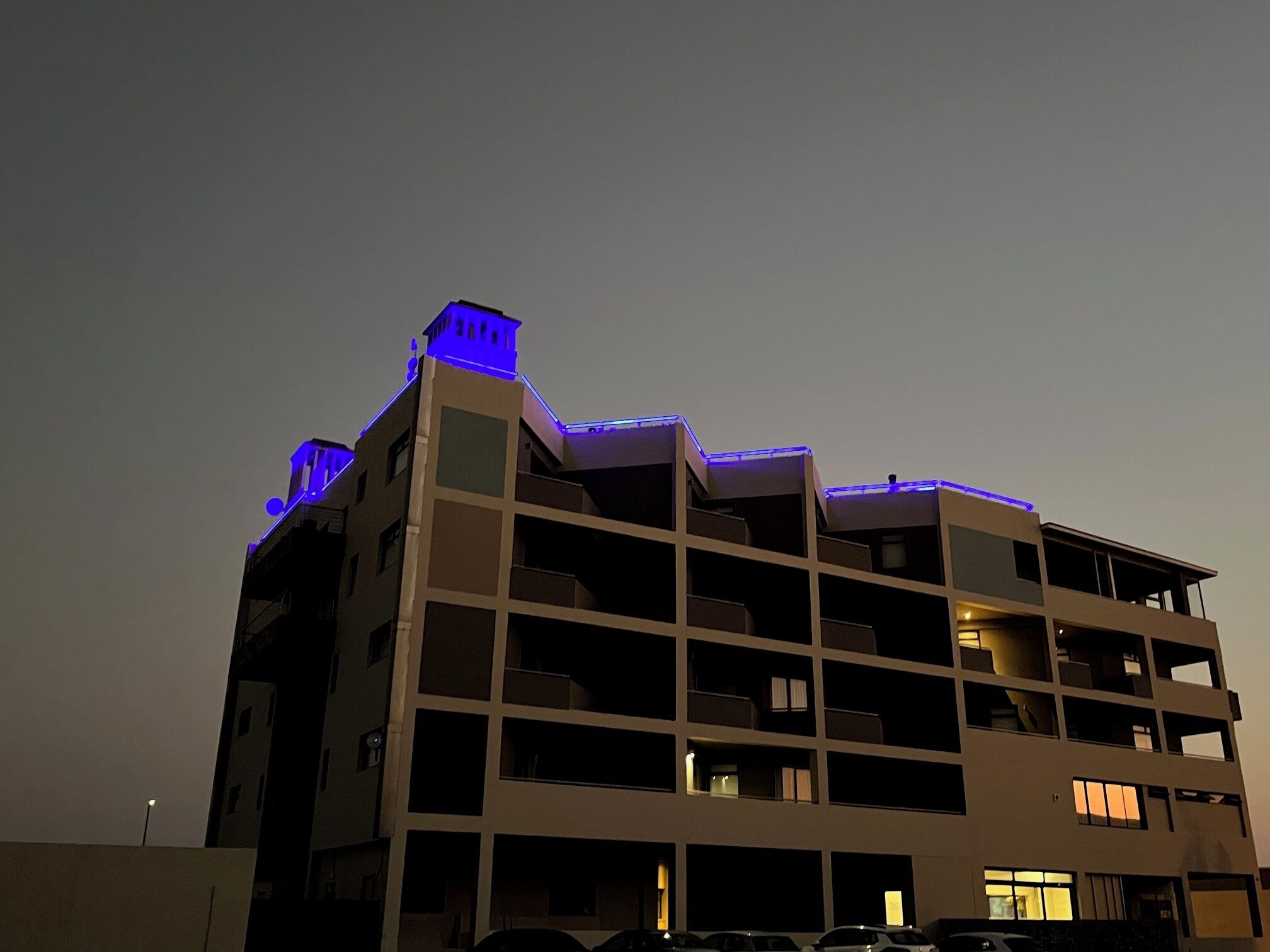 A multi-story building with balconies and a flat roof.