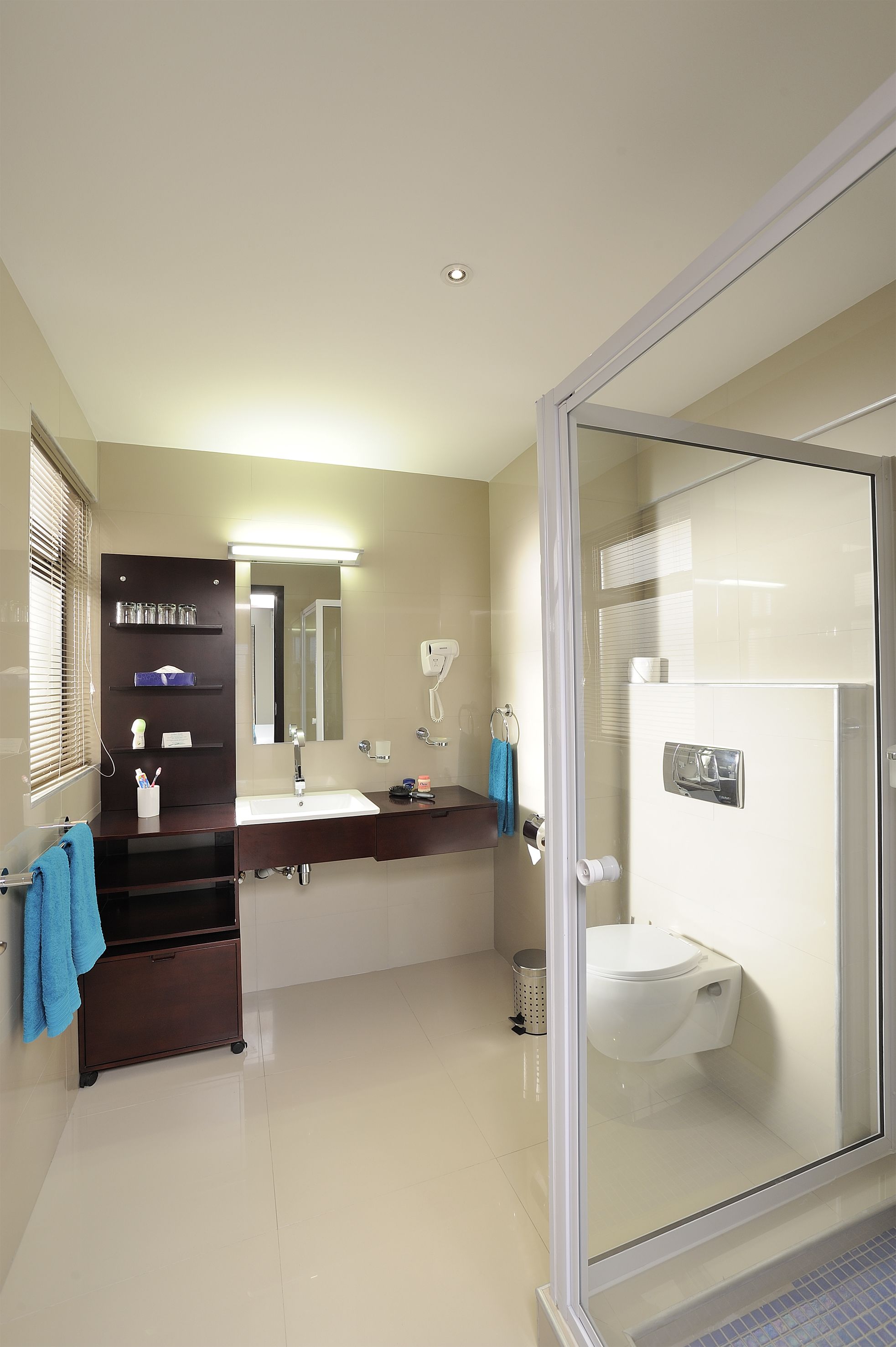 A modern bathroom with a glass shower enclosure, a white sink, and a dark wooden vanity.