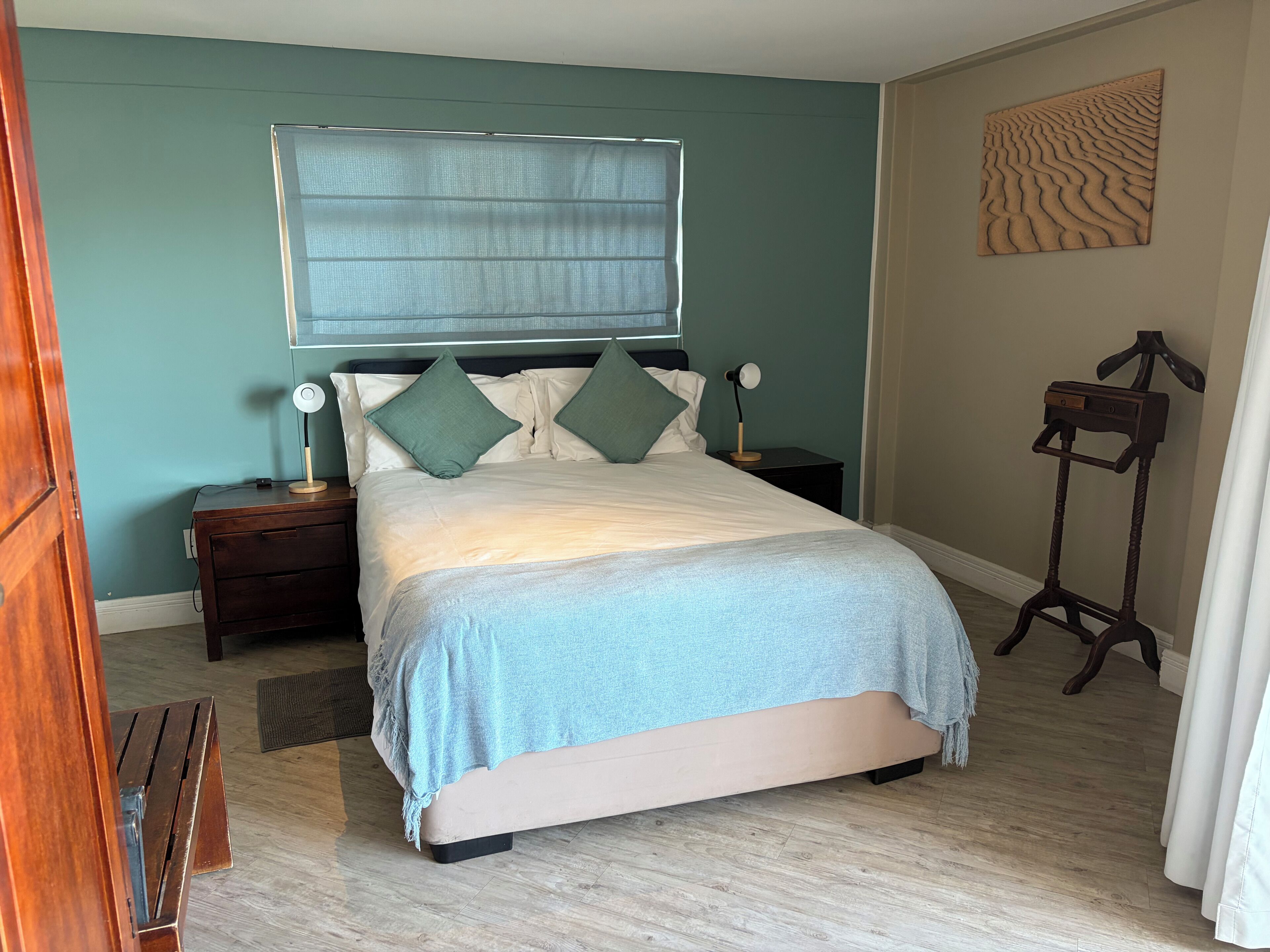 Een slaapkamer met een bed, nachtkastjes, een vloerlamp en een staande lamp.
