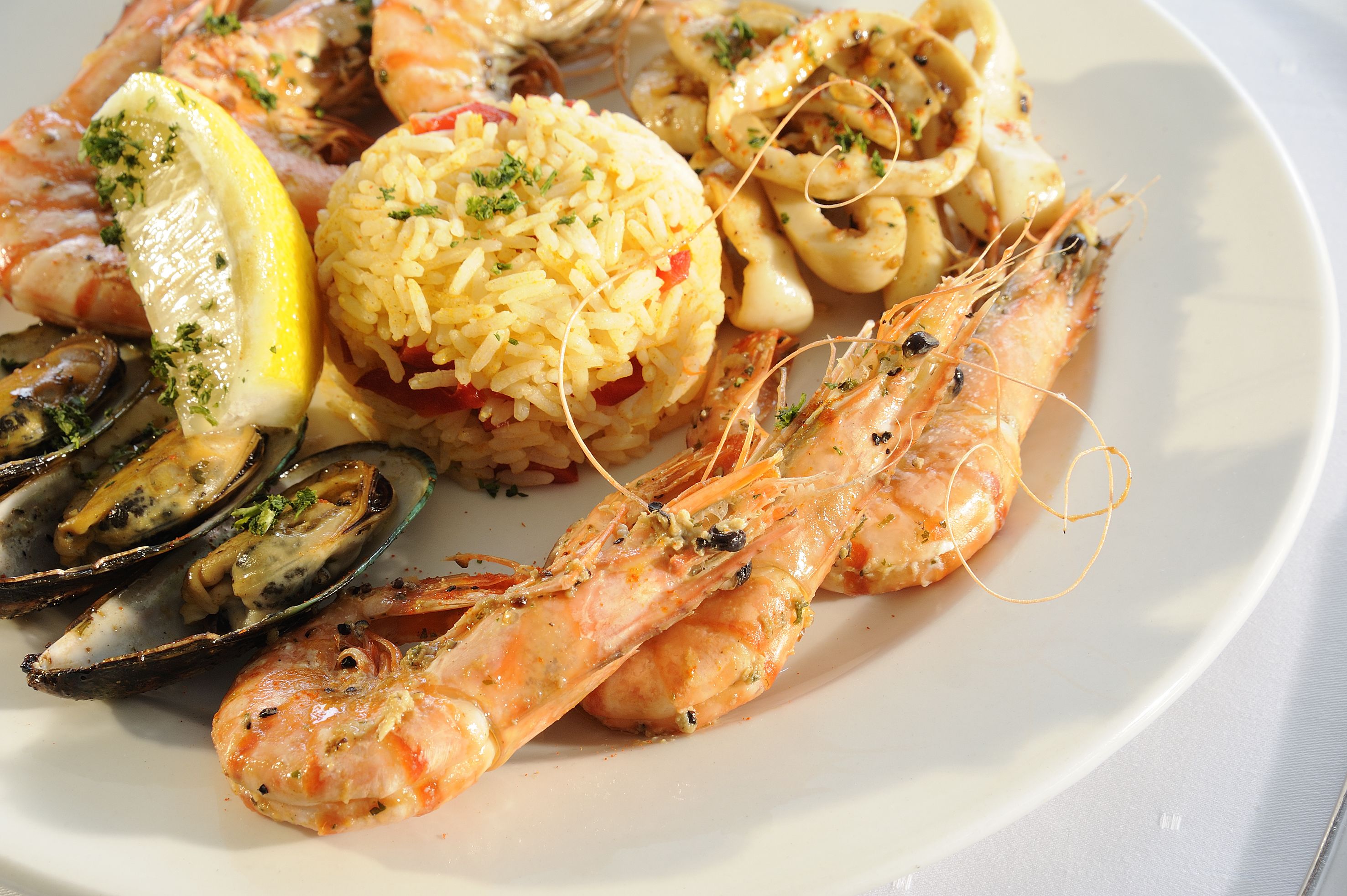 Una bandeja de mariscos con camarones, mejillones y calamares, decorada con hierbas y limón.