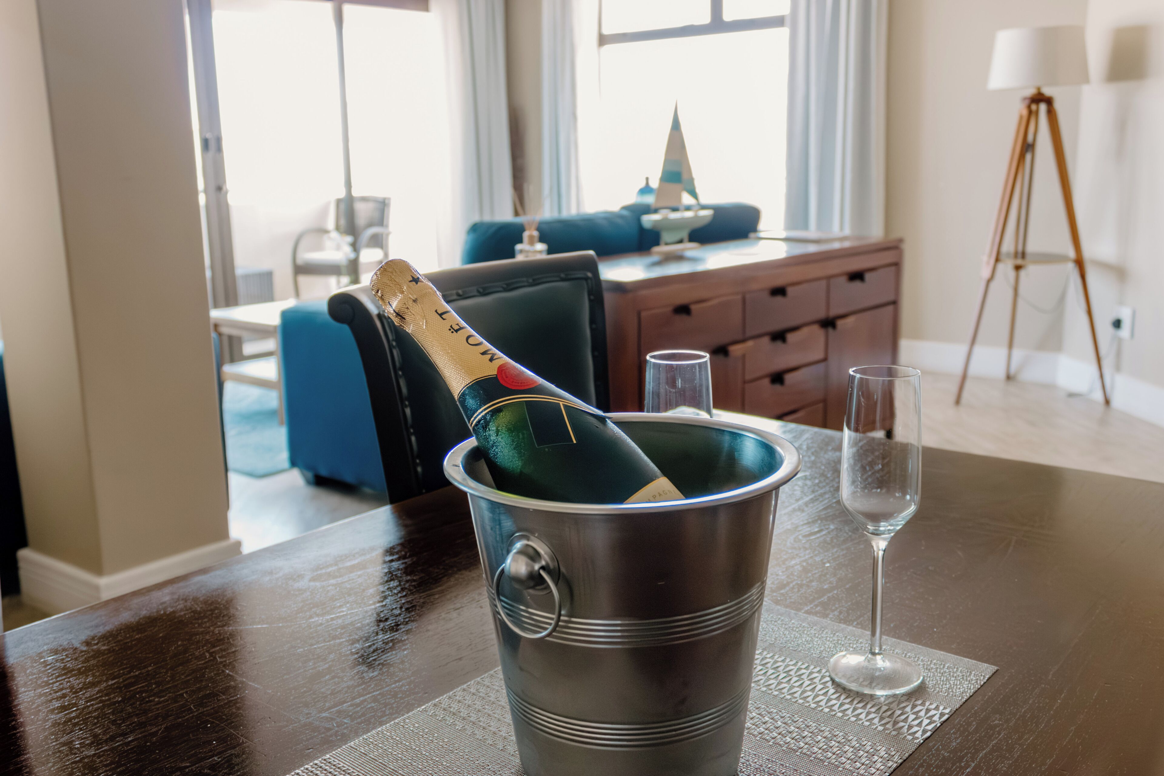 Una habitación con una mesa de comedor, una botella de champán en un cubo y dos copas.
