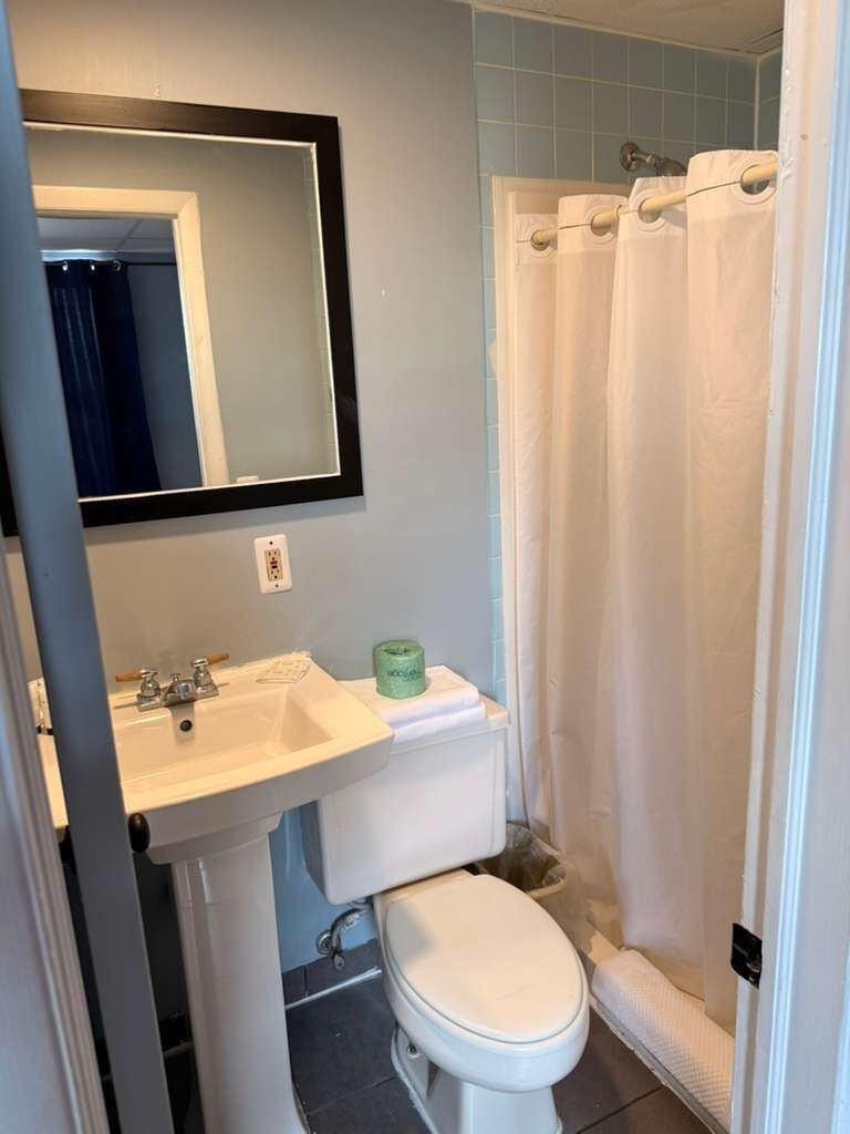 Un baño con lavamanos, inodoro y cortina de ducha.