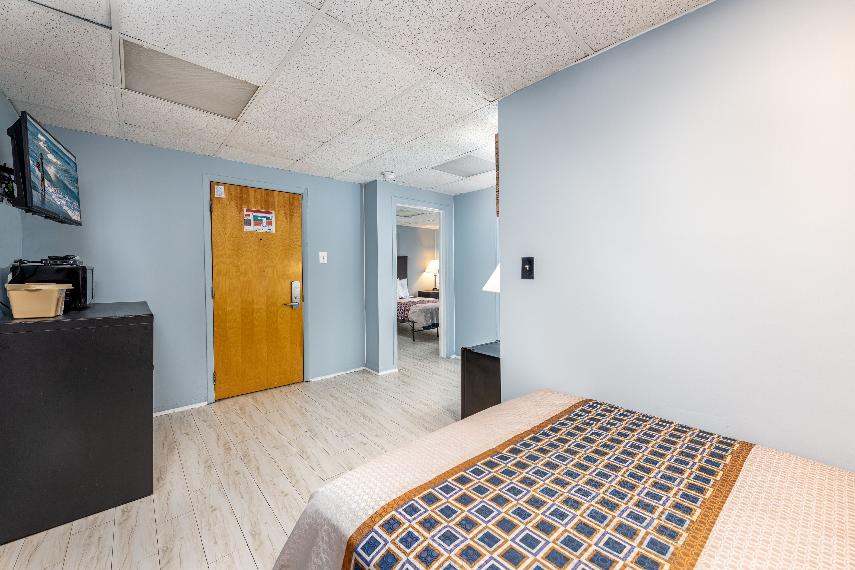 Une chambre d’hôtel comprenant un lit, un bureau, une commode et une porte donnant sur une autre pièce.