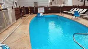 A swimming pool with a wooden fence, lounge chairs, and a pool rule sign. - Hammock Inn & Suites - Jersey Shore (Seaside Heights)
