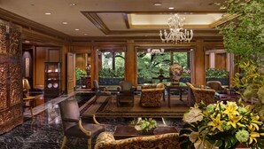 Eine luxuriöse Lobby mit Marmorboden, stilvollem Mobiliar, einem Chandelier und großen Fenstern mit Blick auf Grünflächen.