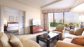 Una habitación de hotel con una cama, televisión, mesa de centro y vistas de la ciudad.