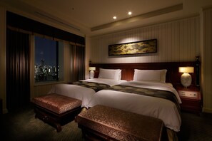 A hotel room with a large bed, two bedside tables, a nightstand, a window with curtains, and a city view. - Hotel Chinzanso Tokyo (Tokyo)