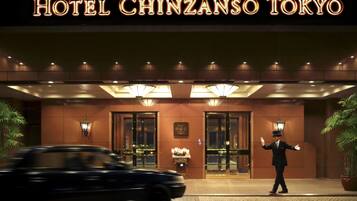 The exterior of Hotel Chinzanso Tokyo with illuminated signage, a welcoming entrance, and a uniformed attendant.