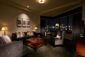 A hotel room with a city view, a sofa, a coffee table, and a chair.
