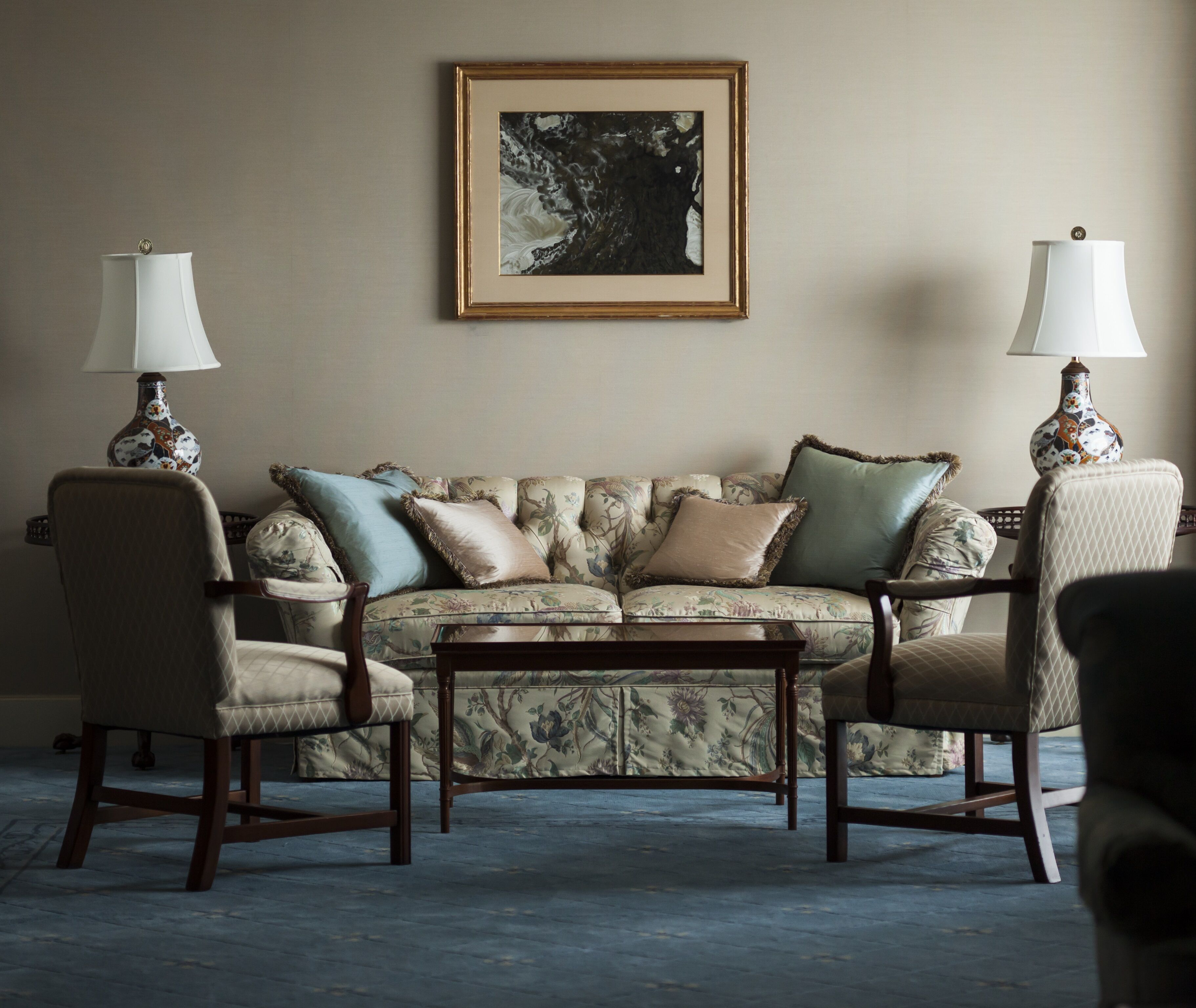 A living room with a floral sofa, two armchairs, a coffee table, and two lamps.