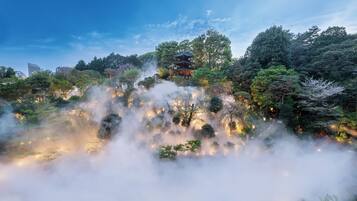 Um pagode japonês tradicional envolto em vegetação exuberante e névoa.