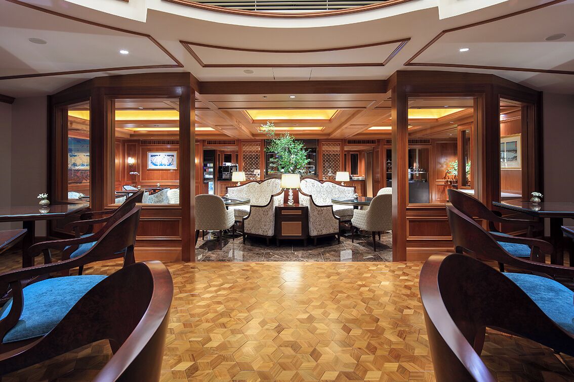A spacious lobby with a central seating area, wooden flooring, and a large plant.