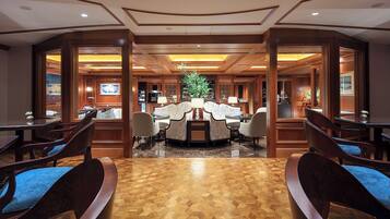 A spacious lobby with a central seating area, wooden flooring, and a large plant.