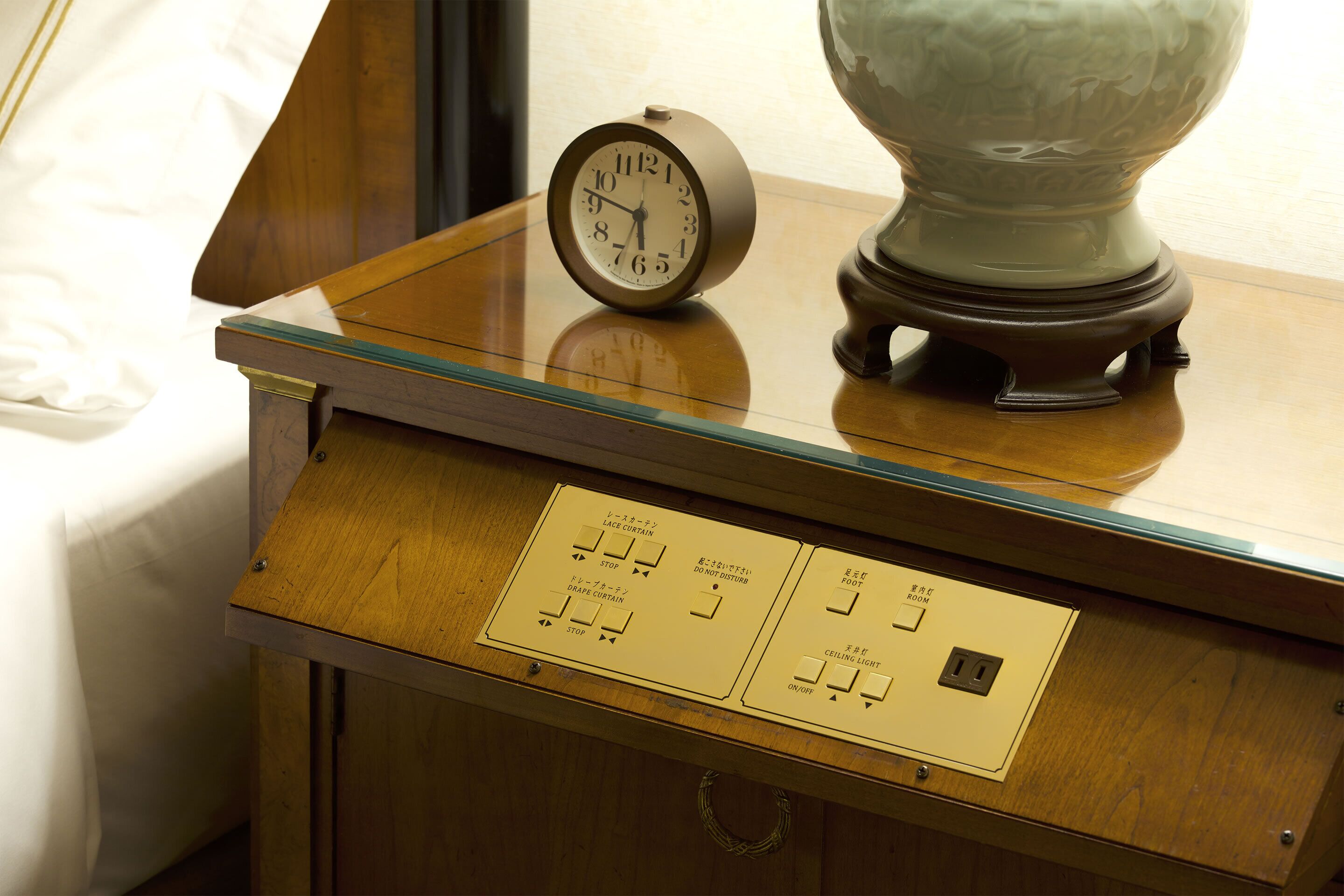 A wooden table with a clock and a lamp.