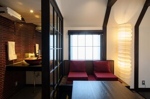 Ein modernes Badezimmer mit einem Holzwaschtisch, einem großen Spiegel und einer roten gepolsterten Bank.