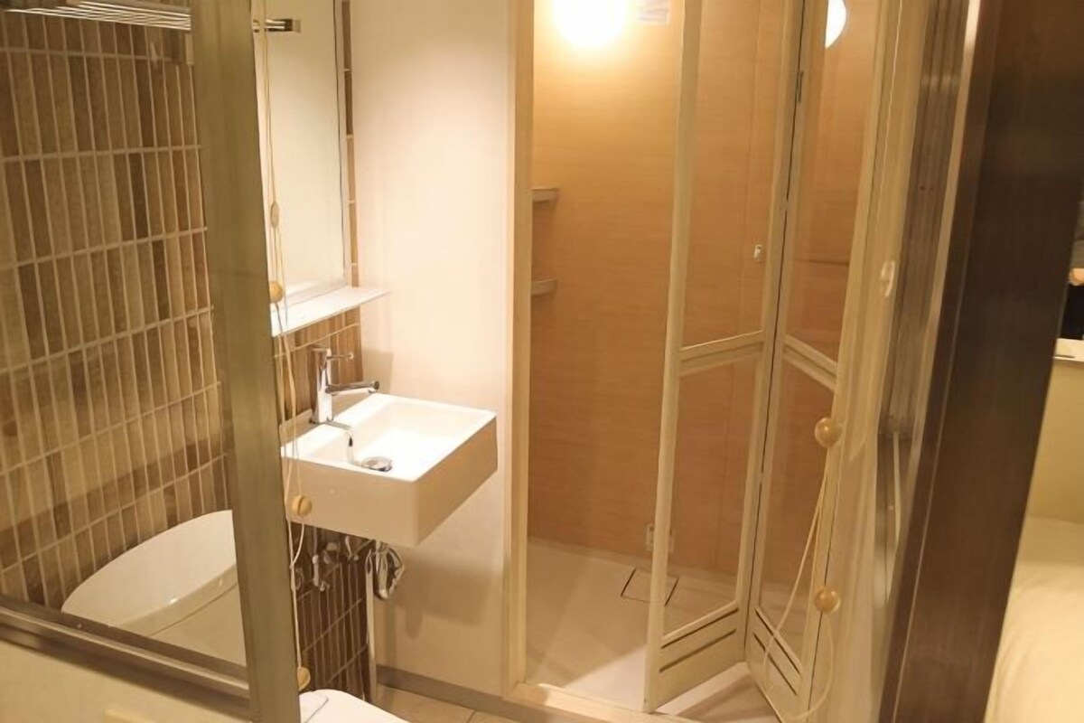 A bathroom with a glass-enclosed shower, a white sink, and a mirror.