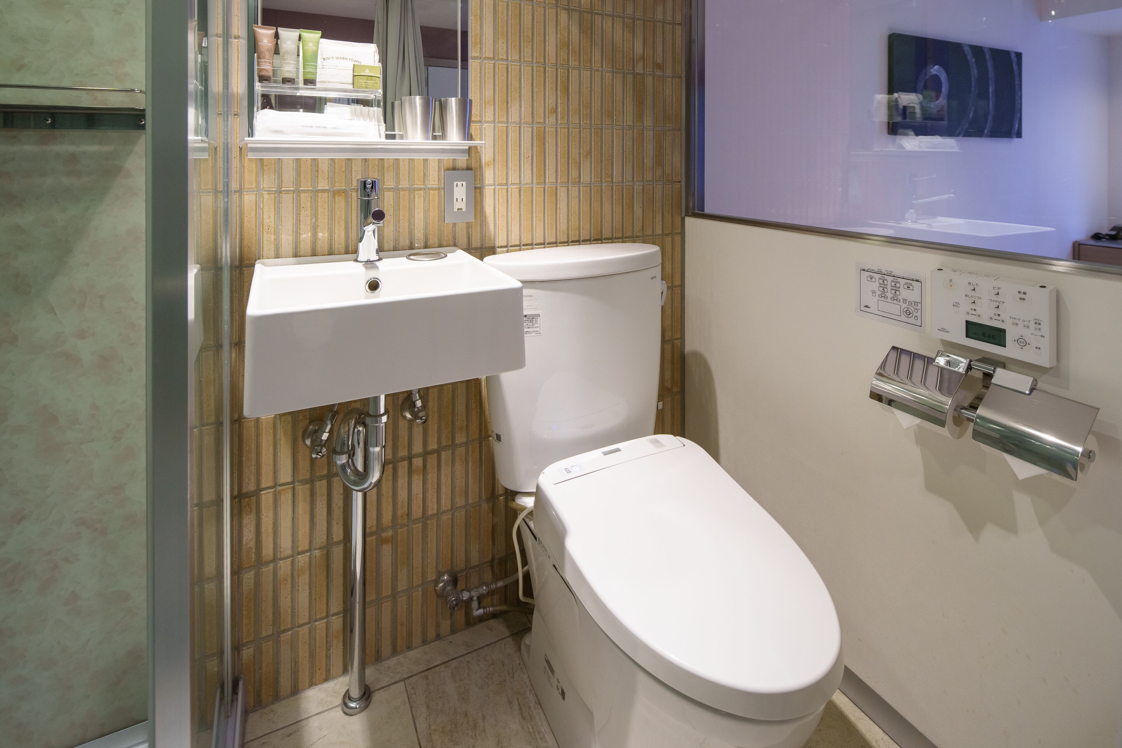 A bathroom with a white sink, toilet, and a control panel on the wall.