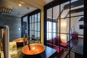 Une salle de bain dotée d’une grande paroi en verre, d’un banc en bois et d’un grand lavabo rond de couleur orange.