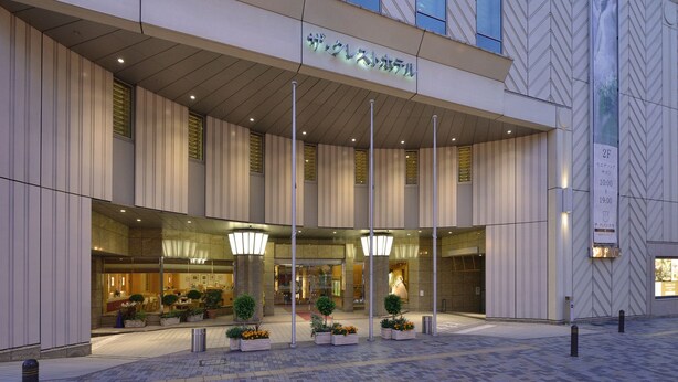 Una entrada de hotel moderna con fachada de vidrio, asientos al aire libre y un letrero que indica el nivel 2F.
