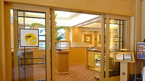 Un hall de hotel con mostrador de recepción, una vitrina de vidrio y suelo alfombrado.