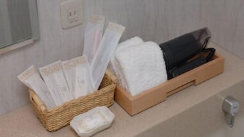 A bathroom with a wooden tray holding toiletries, a white towel, and a black towel.