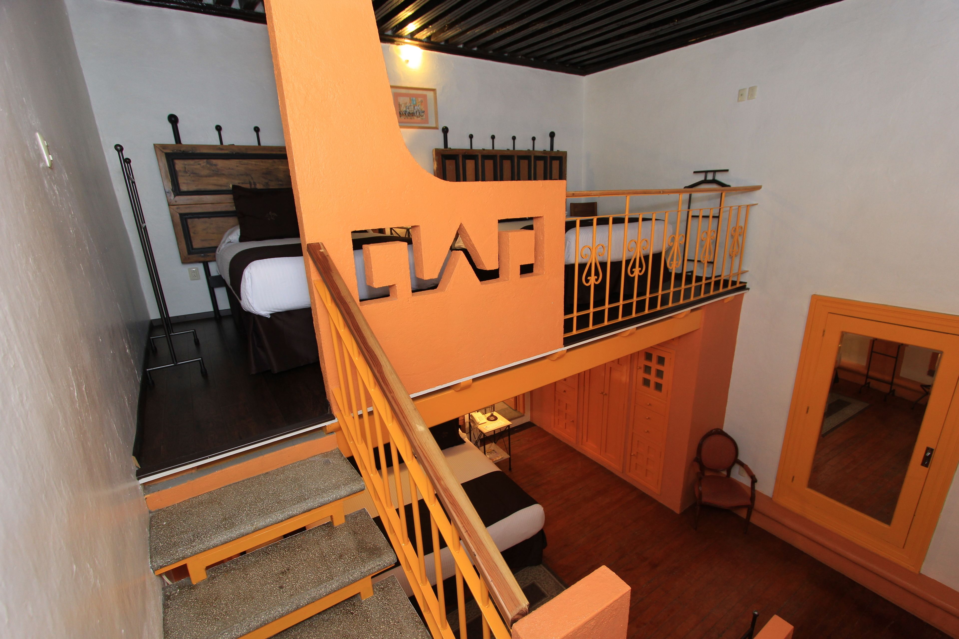 Habitación de varios niveles con escalera, cama, escritorio y silla.