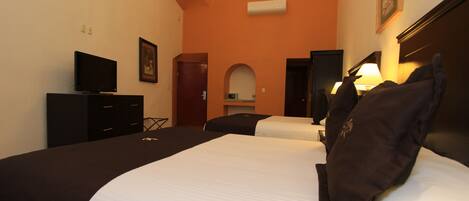 A hotel room with two beds, a TV, a chandelier, and a picture on the wall.