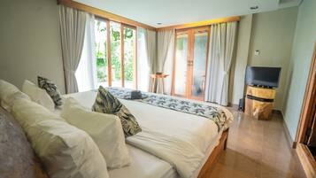 A bedroom with a large bed, a TV, and a sliding glass door to a balcony.