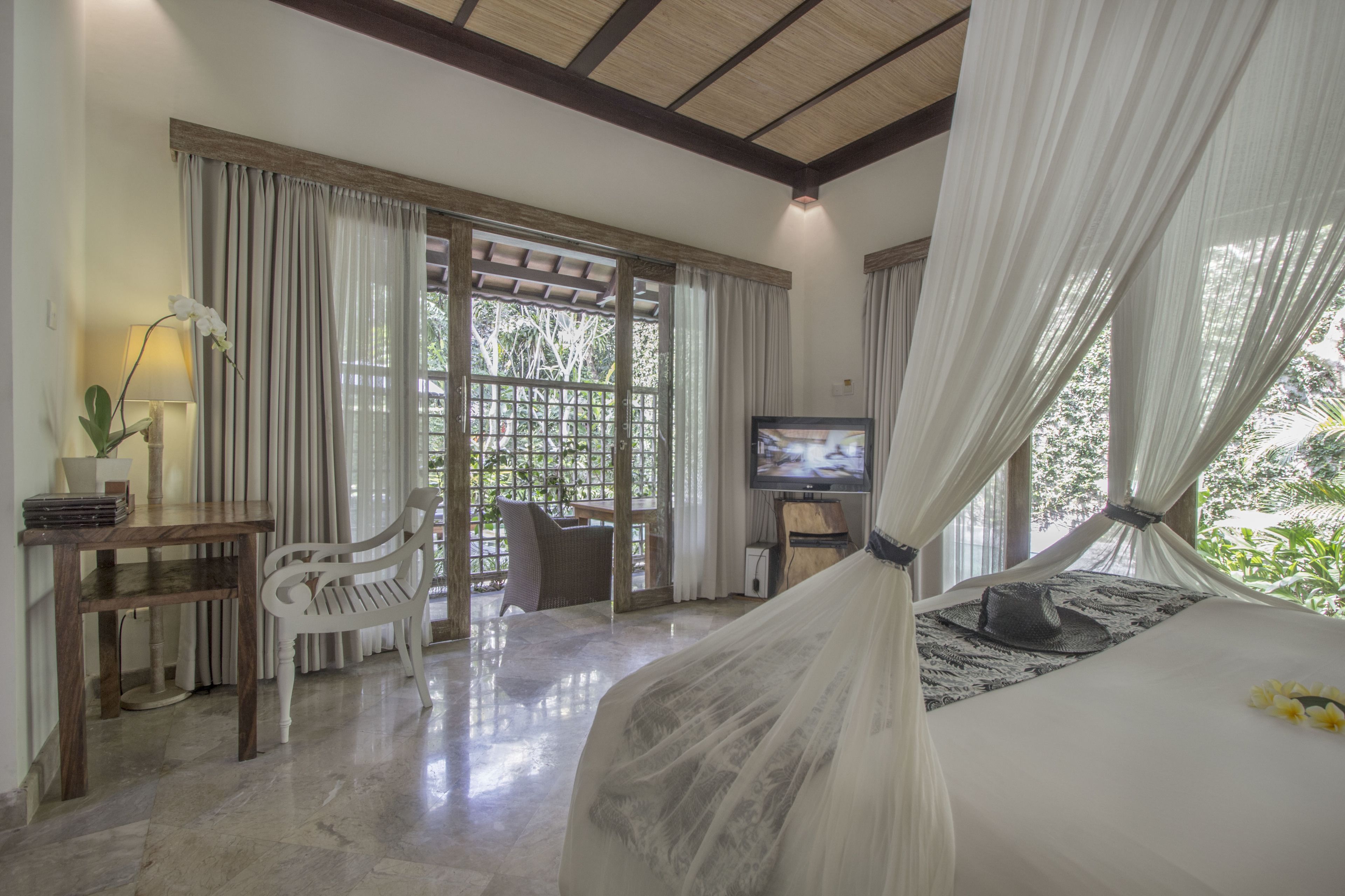 Un dormitorio con una cama, televisión, escritorio y silla.