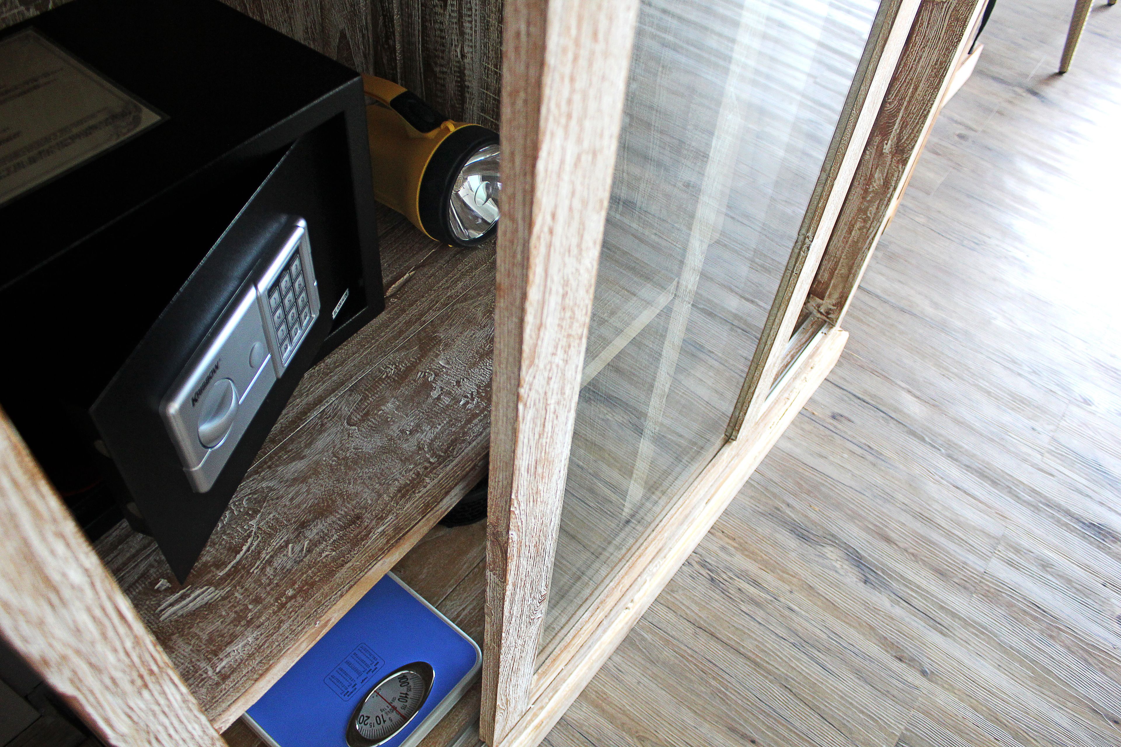 A wooden floor, a scale, and a black device with a keypad.