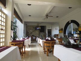 Ein Restaurant mit Holztischen und -stühlen, weißen Tischdecken und einem Deckenventilator.