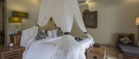 A bedroom with a four-poster bed, a bedside table, a nightstand, a wooden bench, and a small bedside table with a lamp.