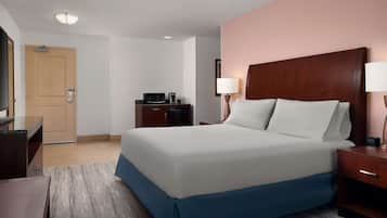 A hotel room with a large bed, bedside lamps, a desk, a microwave, and a door.